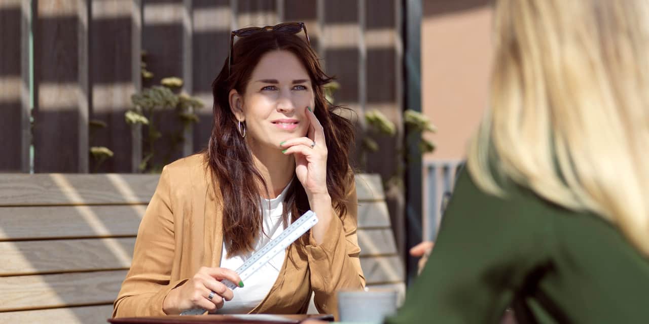 Two people sitting outside by a table.