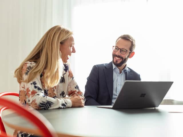Two people talking to each other sitting by a table.